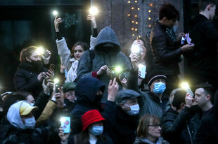 Demonstranten mit Corona-Masken und leuchtenden Handy-Lampen