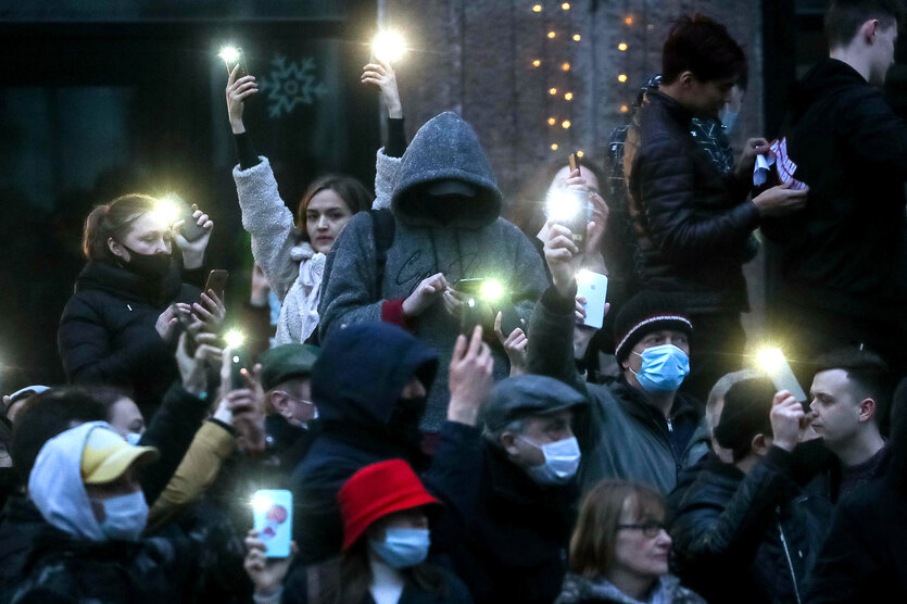 Demonstranten mit Corona-Masken und leuchtenden Handy-Lampen