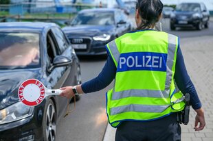 Eine Polizisitin hält eine Haltekelle vor einem Fahrzeug