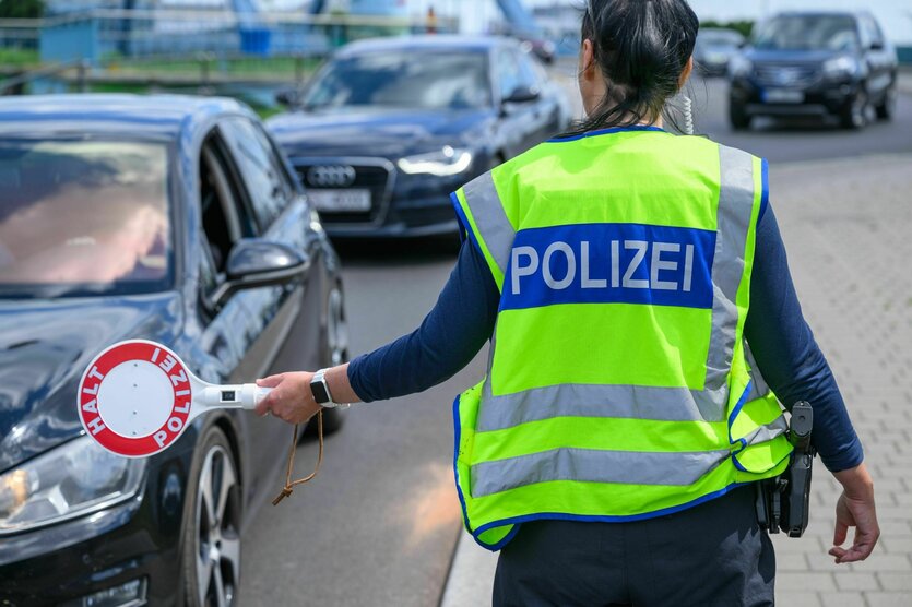 Eine Polizisitin hält eine Haltekelle vor einem Fahrzeug