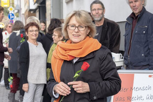 Gudrun Christ, Geschäftsführerin von Pro Familia Baden-Württemberg, steht mit einer Rose in der Hand vor der Pro-Familia-Beratungsstelle in Pforzheim, im Hintergrund stehen Mitarbeiter.