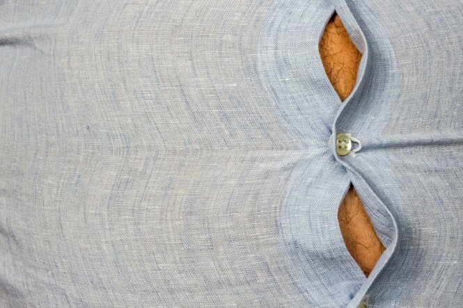 Ein Hemd spannt sich über den Bauch eines Mannes