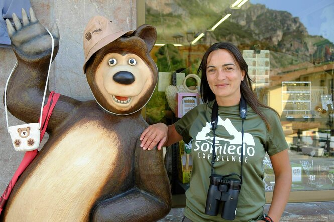 Sofia Gonzales, steht neben der Plastikfigur eines Comic-Bären, sie trägt ein grünes T-Shirt, das auf "Somiedo Experience" hinweist