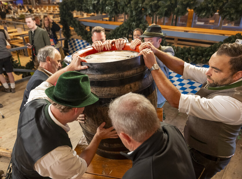 Männer in Trachten heben ein Bierfass