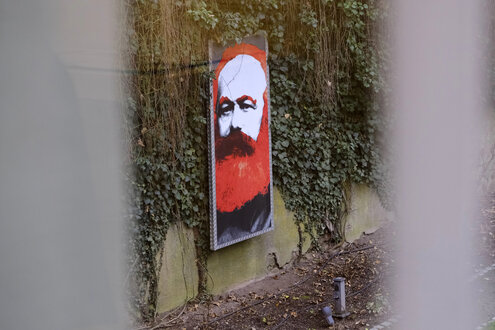 Das colorierte Porträt eines Mannes lehnt an einer Wand, die mit Efeu bewachsen ist