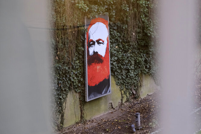 Das colorierte Porträt eines Mannes lehnt an einer Wand, die mit Efeu bewachsen ist