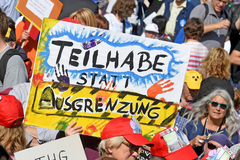 Menschen stehen zusammen und halten bunte Schilder hoch