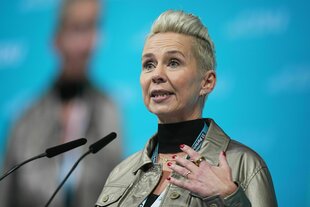 Eine Frau spricht an einem Rednerpult in ein Miktofon