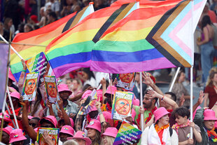 Menschen mit rosa Hüten schwenken Regenbogenfahnen