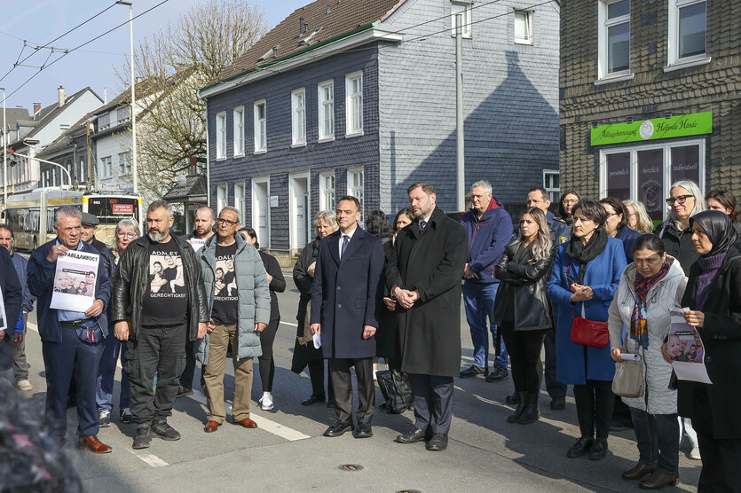 Eine Gruppe von Menschen hält eine Mahnwache mit Bildern ab.