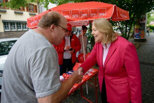 Bärbel Bas unterhält sich vor einem Wahlkampfstand der SPD mit einem Mann