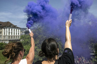 Frauen demonstrieren mit lila Rauchkanonen
