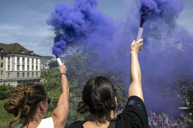 Frauen demonstrieren mit lila Rauchkanonen