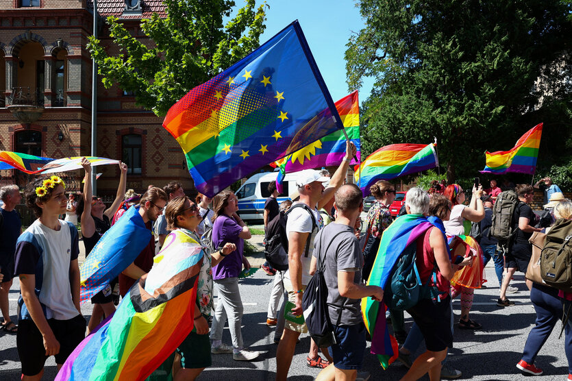 Demonstranten laufen mit Regenflagge auf der Straße