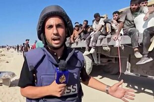 Anas al-Sharif mit Helm und Mikrofon vor der Kamera, im Hintergrund sitzen Männer auf einem Lkw