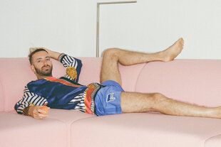 Der Maler Navot Miller liegt lasziv auf einem eckigen rosa Sofa