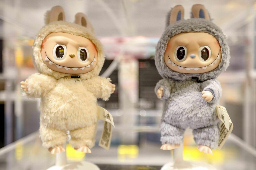 Zwei Labubu-Plüschfiguren mit großen Augen und einer breiten Zahnreihe grinsen aus dem Schaufenster