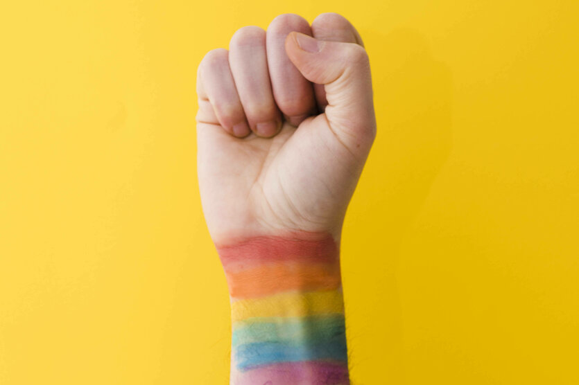 Eine gereckte Faust mit Regenbogenfarben am Handgelenk