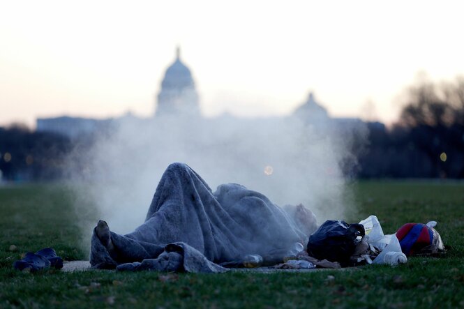 Obdachlose Person liegt auf der Wiese