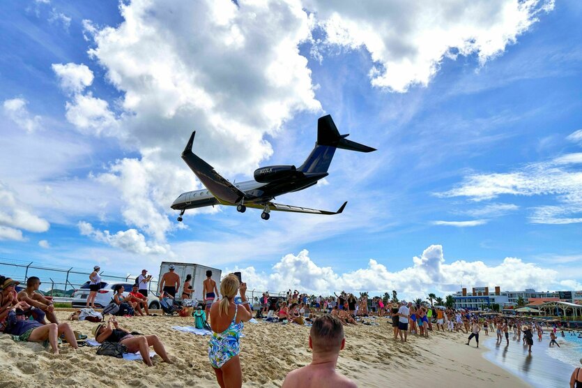 En Flugzeug fliegt über die Köpfe von Urlaubern am Strand