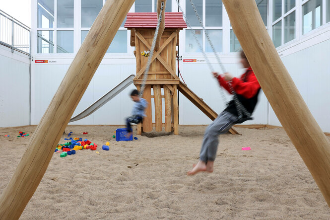 Kinder auf einer Schaukel in der Flüchtlingsunterkunft Tegel