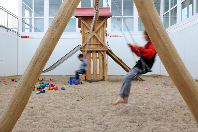 Kinder auf einer Schaukel in der Flüchtlingsunterkunft Tegel