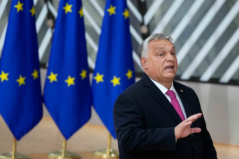 Viktor Orbán steht vor Flaggen der EU