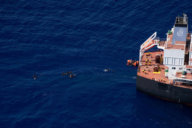 Menschen schwimmen im Meer während einer Bergungsaktion durch ein Frachtschiff im zentralen Mittelmeer zwischen Libyen und Tunesien.