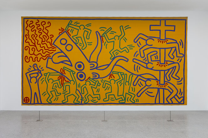 Ein Graffito von Keith Haring zeigt bewaffnete Männchen, die auf einen großen Ochsen einschlagen, und andere Männchen, die auf Christenkreuze aufgespießt sind