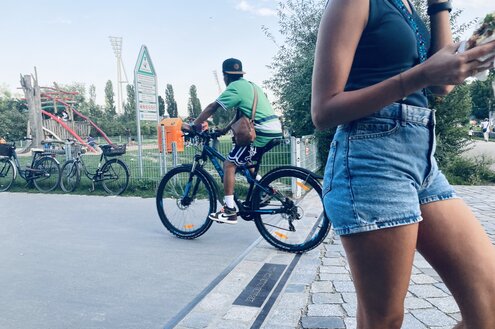 Ein Radfahrer und eine Fußgängerin über der Grenzmarkierung im Mauerpark