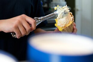 Arbeit in der Eisdiele: Eine Schülerin portioniert Eis mit einem Eislöffel