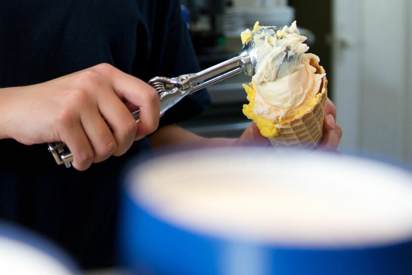 Arbeit in der Eisdiele: Eine Schülerin portioniert Eis mit einem Eislöffel