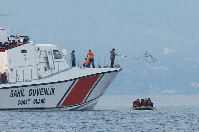 Ein Schiff der Küstenwache und ein Schlauchboot mit mehreren Personen.