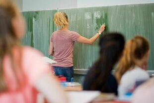 Eine junge Lehrerin schreibt an einer Schultafel