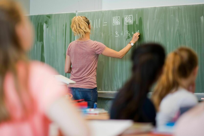 Eine junge Lehrerin schreibt an einer Schultafel