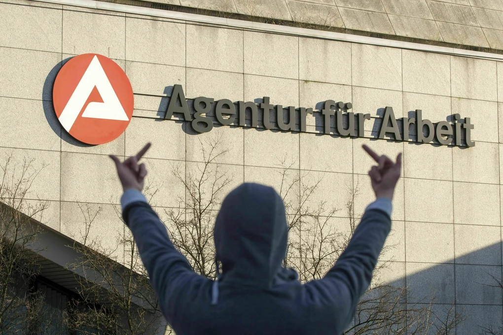 Symbolfoto - Person von hinten zeigt dem Jobcenter den Mittelfinger