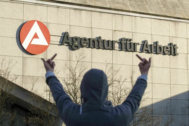Symbolfoto - Person von hinten zeigt dem Jobcenter den Mittelfinger