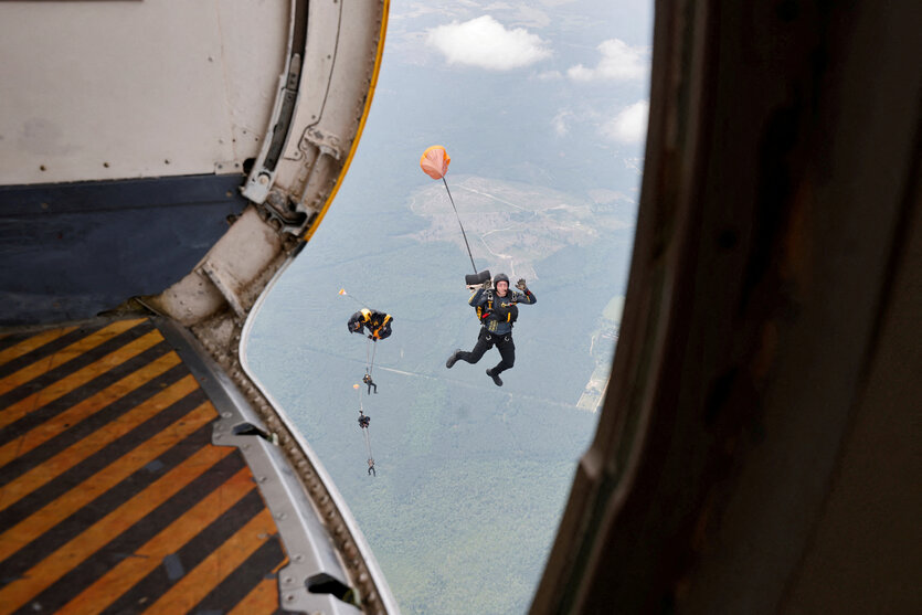 Blick aus einem Flugzeug auf eine Person, die mit Fallschirm rausspringt
