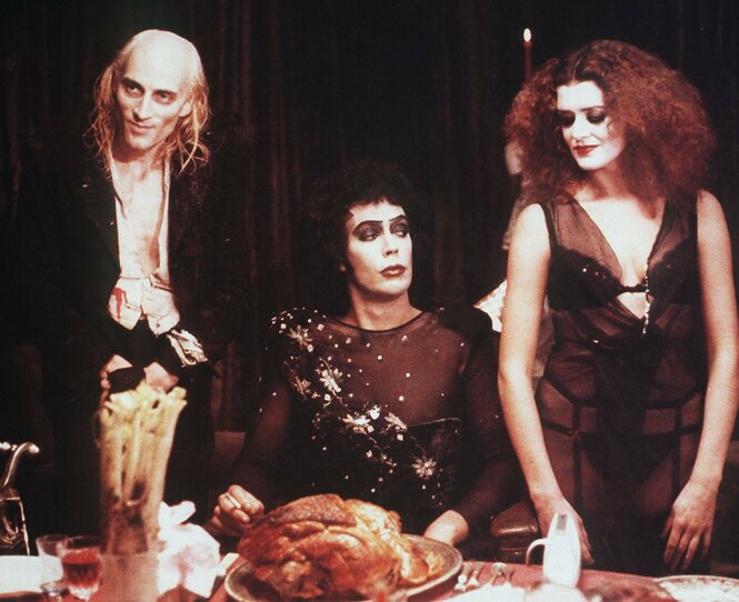 Ein gebraterner Vogel auf dem Tisch bei Frank N. Furter (Tim Curry, M.), daneben stehen Riff Raff (Richard O’Brien) und Magenta (Patricia Quinn)