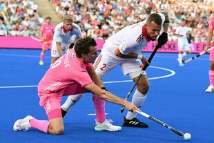 Deutschlands Johannes Große in zartrosa Trikot (l) und Polens Mikolaj Glowacki kämpfen mit Hockeyschlägern um den Ball