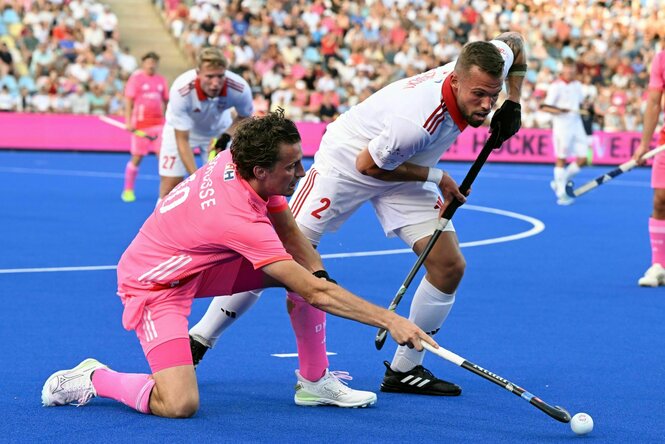 Deutschlands Johannes Große in zartrosa Trikot (l) und Polens Mikolaj Glowacki kämpfen mit Hockeyschlägern um den Ball