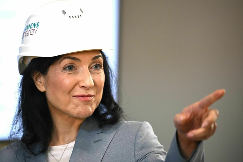 Eine Frau mit weißen Schutzhelm zeigt mit dem Finger