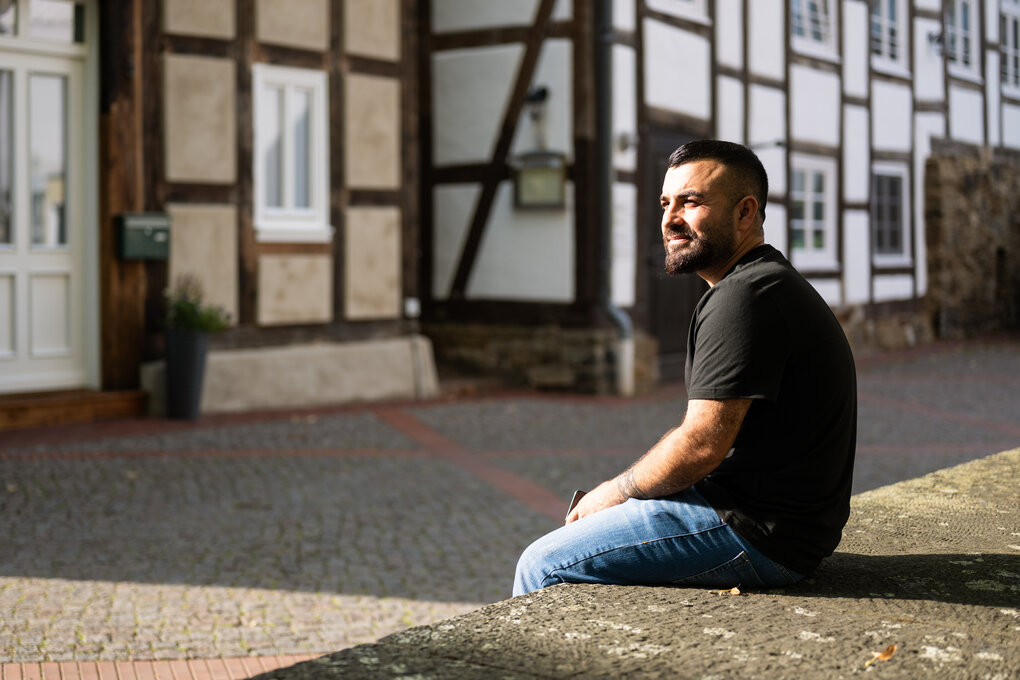 Porträt von Faisal Zendinan in einer Straße mit Fachwerkhäusern.