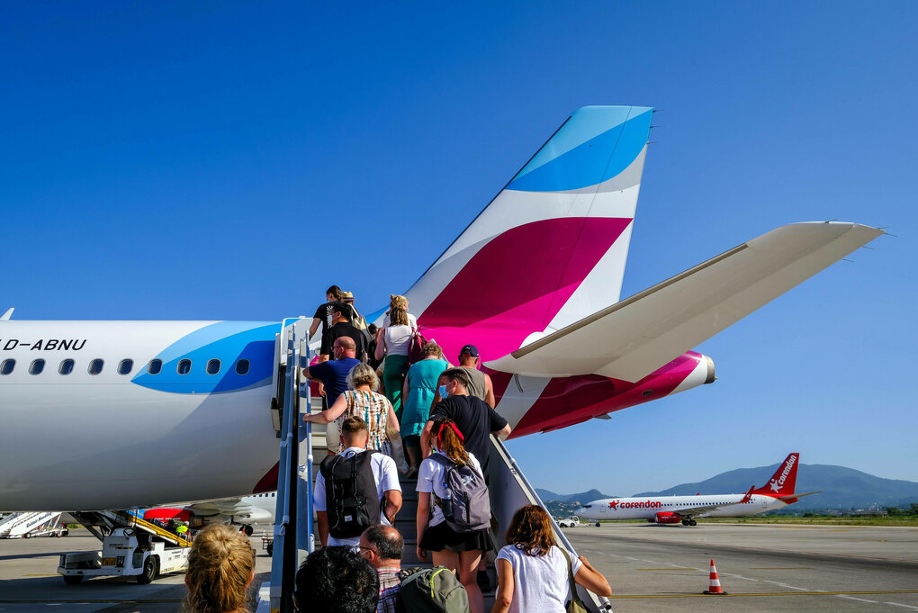 Am Flughafen Korfu steigen Urlauber ueber eine Aussentreppe auf dem Vorfeld in ein Eurowings Flugzeug