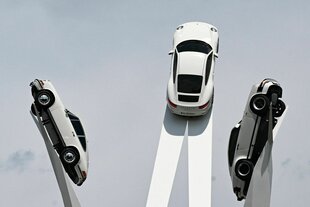 Drei Porsches streben himmelwärts auf einer Kunstinstallation