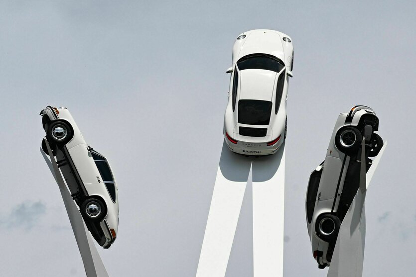 Drei Porsches streben himmelwärts auf einer Kunstinstallation