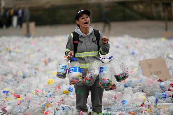 Eine Recyclerin watet durch Plastikflaschen