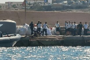Beamte der italienischen Küstenwache tragen einen Leichensack auf dem Dock des Hafens von Lampedusa