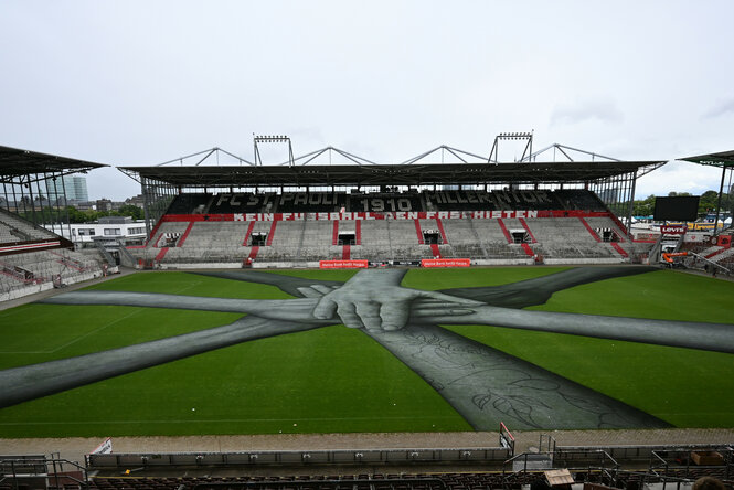 Menschenhände auf dem Spielfeld im Millerntor-Stadion: Kunstwerk des Künstlers Saype bei der diesjährigen „Millerntor Gallery“