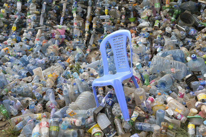 Ein Plastikgartenstuhl in einem Plastikflaschenmeer